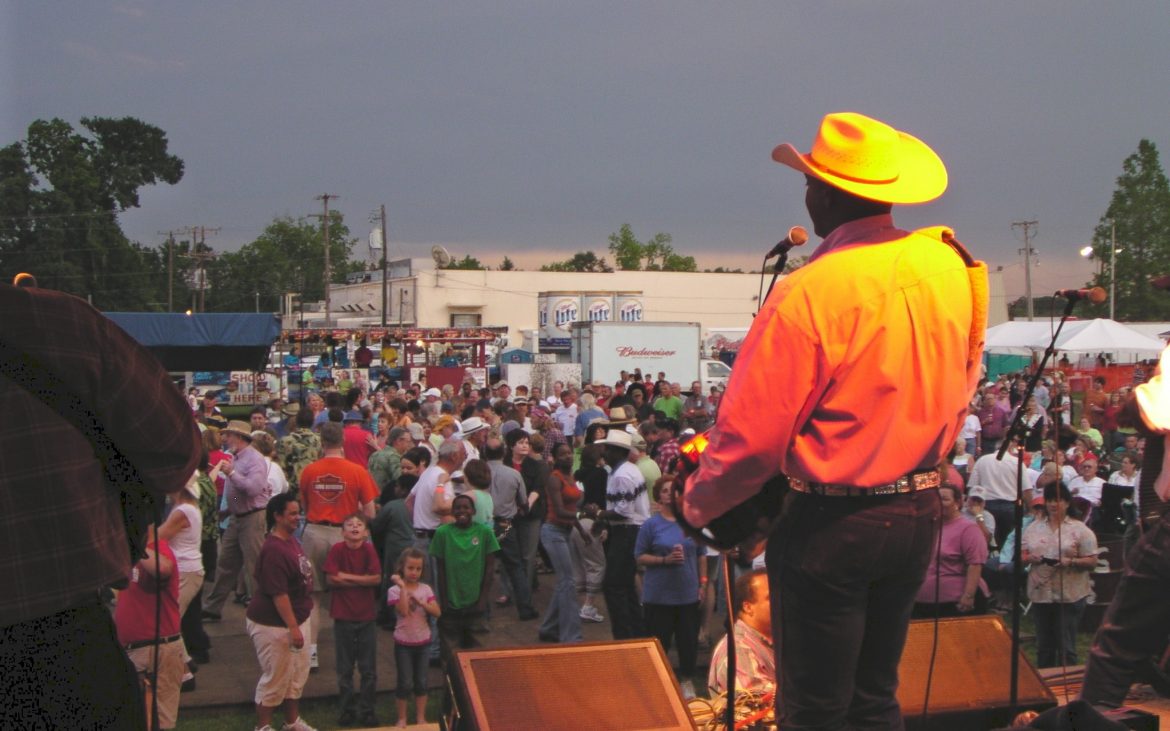 Man in yellow shirt and hat addressing a crowd