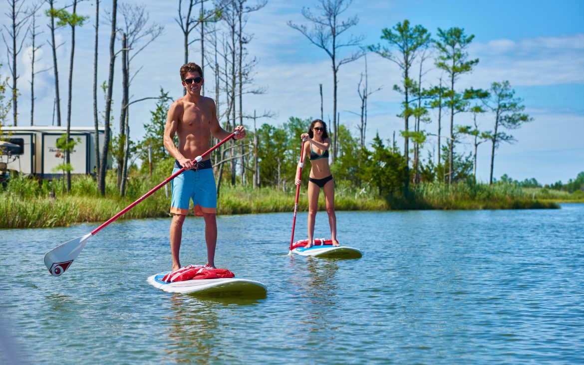 Man and woman in bathing suits atop paddle boards in the water
