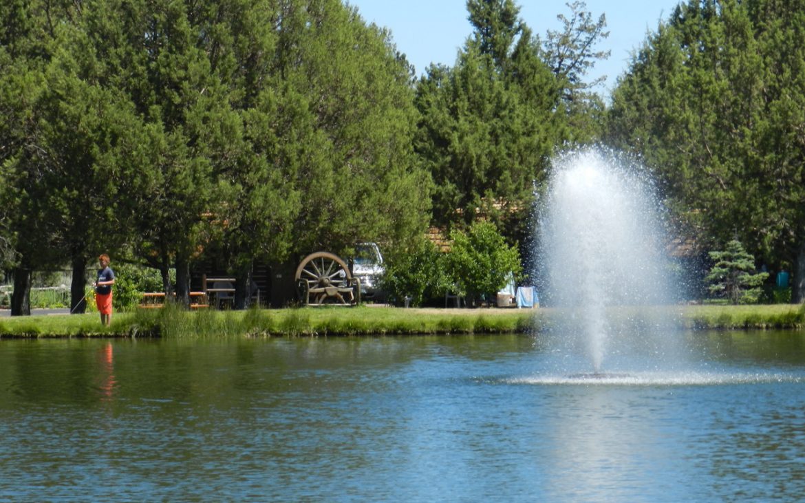 Flowing fountain in the middle of a blue lake with trailers in background