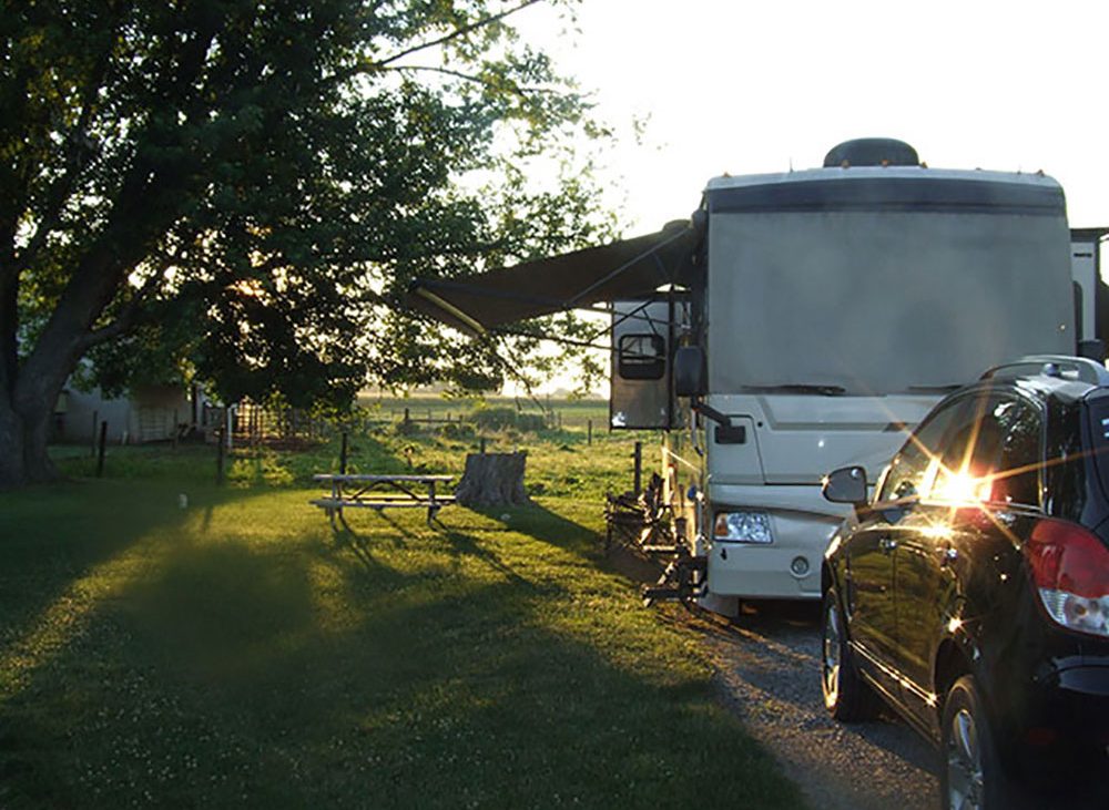 Large white RV with awning extended parked along grassy spot