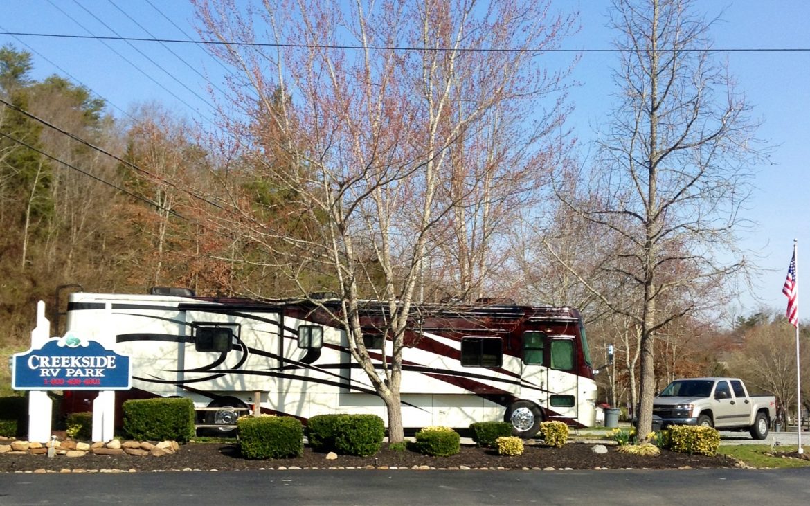 Large white and brown RV parked beside blue side