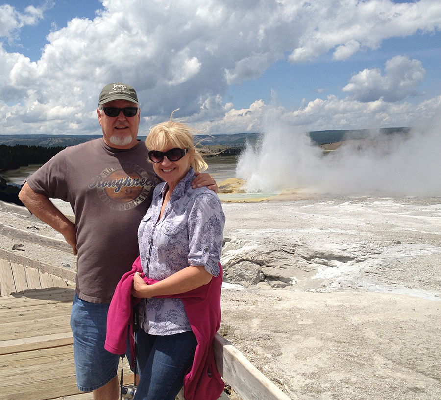 A couple in front of Old Faithful Geyser in Yellowstone.