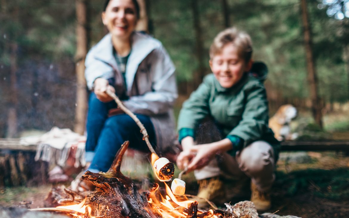 Mother and son cook marshmallow candies on the campfire