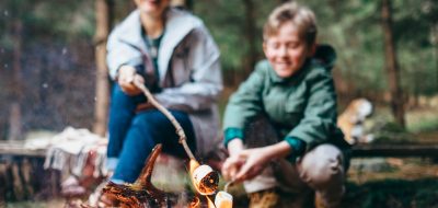 Mother and son cook marshmallow candies on the campfire