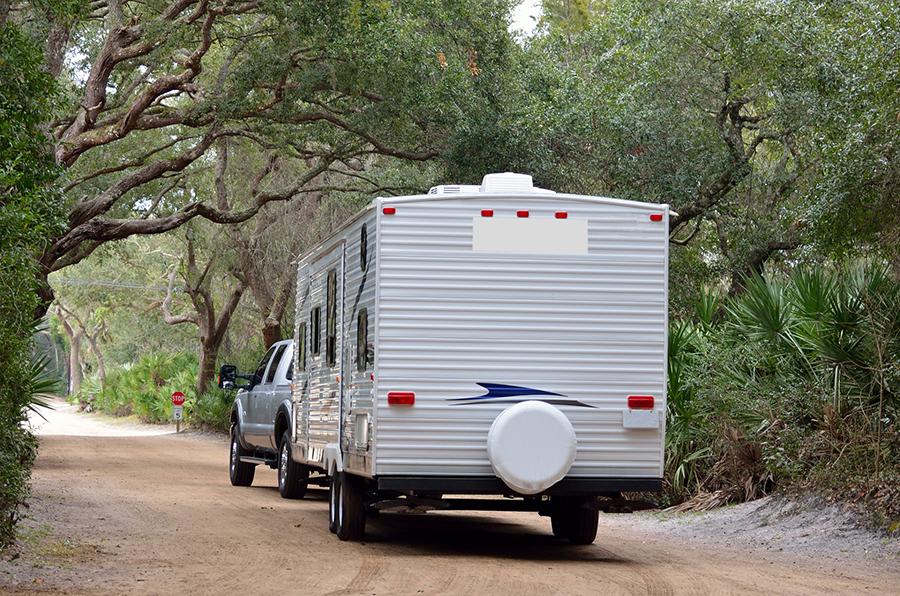 A travel trailer cruising down a dirt road.