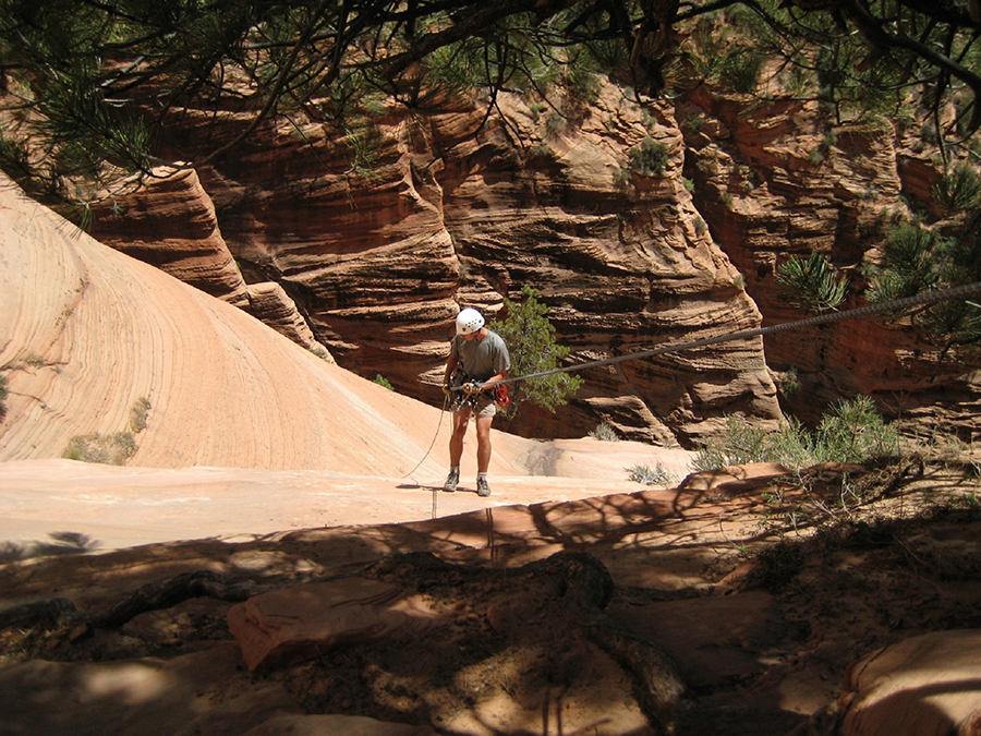 A climber rappels down a steep slope.