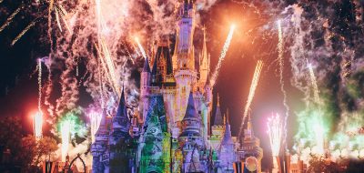Colorful lit Disney castle at night with fireworks exploding