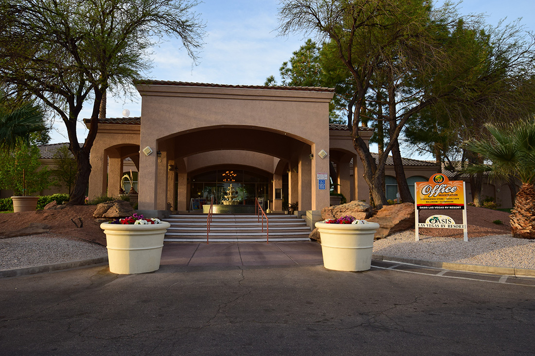 Flanked by large planters that grow flowers, a stairway leads to the adobe-style entrance to the office complex of Oasis Las Vegas RV Resort.