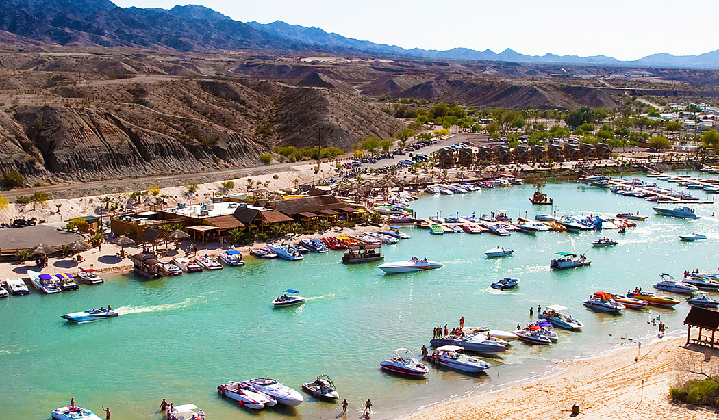Boats crowd an inlet from the Colorado River with rugged hills and bluffs in the background at Pirate Cove RV Resort.