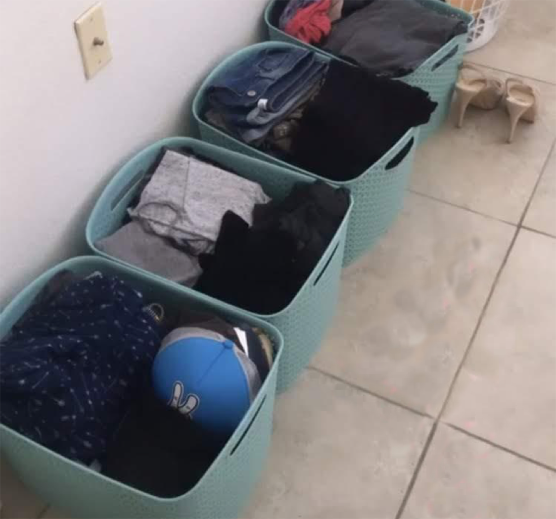Four bins on the floor with clothing organized inside.