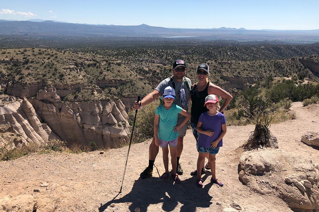 Two parents and their children stand before a rugged backdrop of desert.