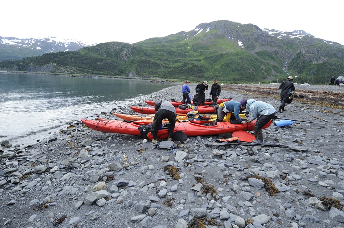 Kayakers prepare their vessels on the rocky shores of Prince Williams Sound.
