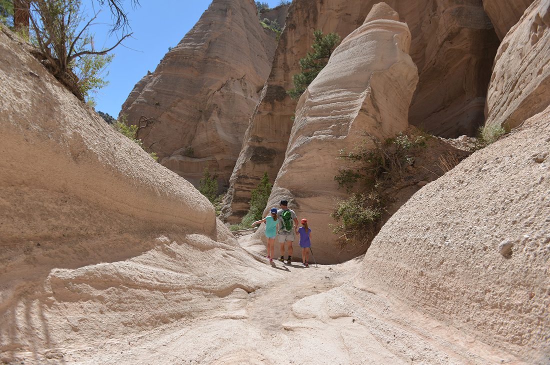 Hiking a trail into a ravine at Tent Rocks National Monument.