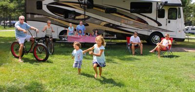 A family plays on a lawn near a motorhome.