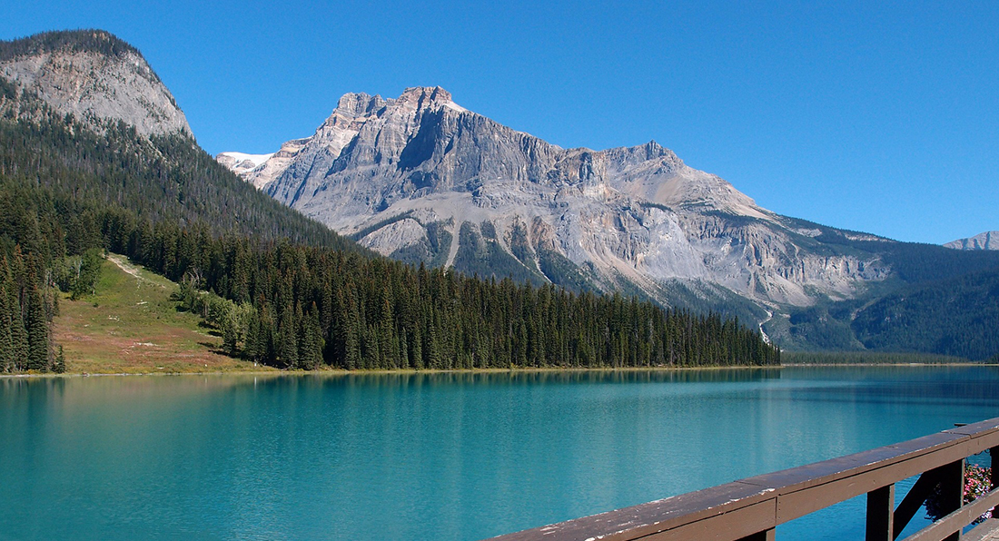 Beautiful emerald lake with pine trees and snow covered mountains