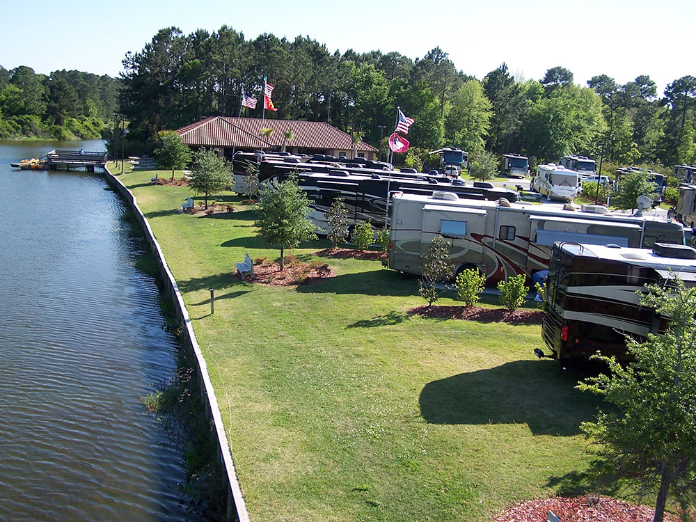 RVs parked along a strip of lawn and a tranquil waterway.