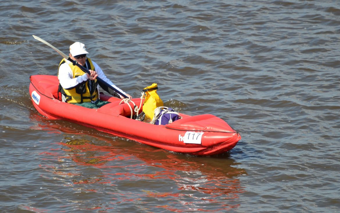 Man paddling on a red inflatable kayak.