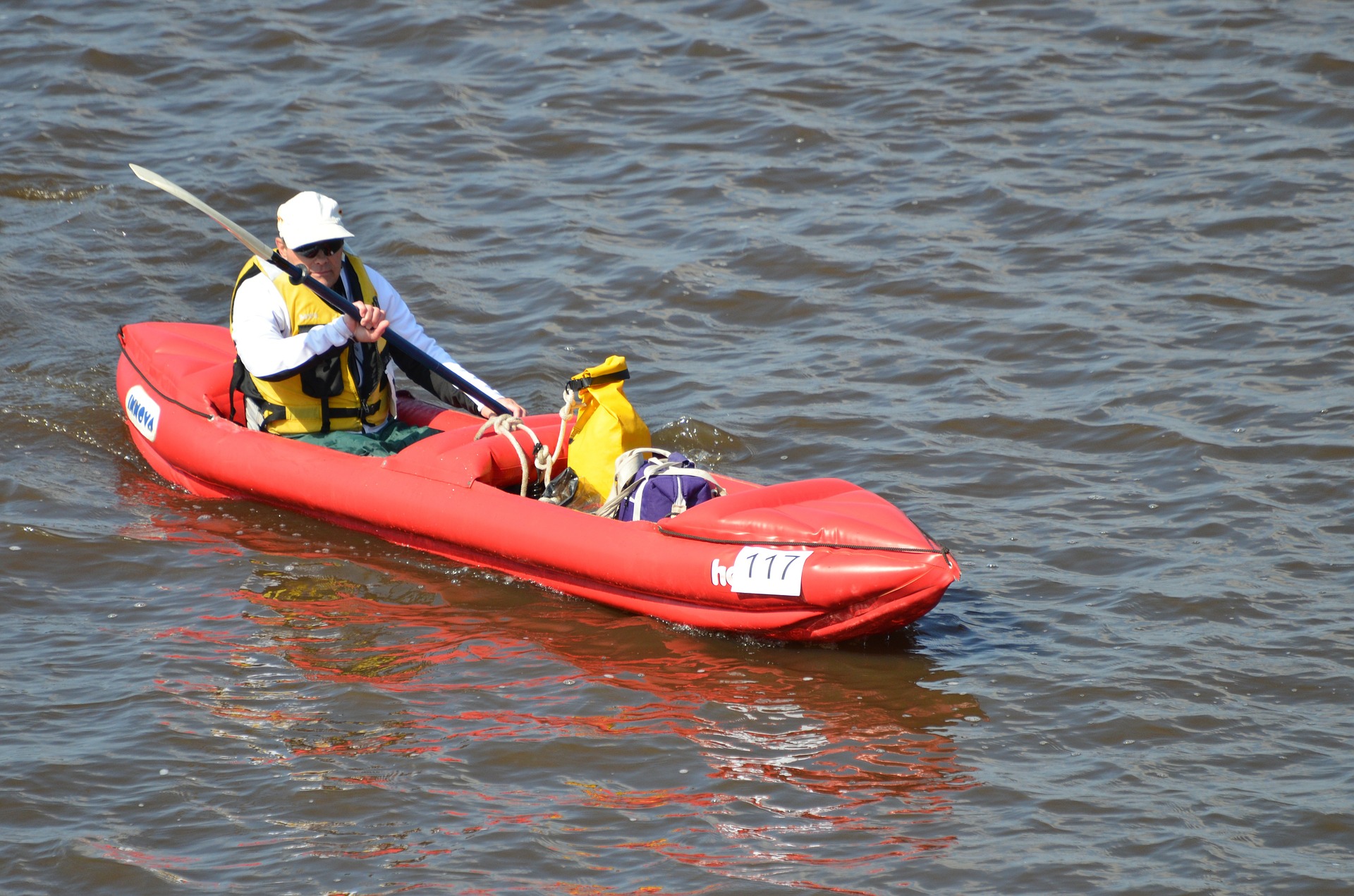 Man paddling on a red inflatable kayak.