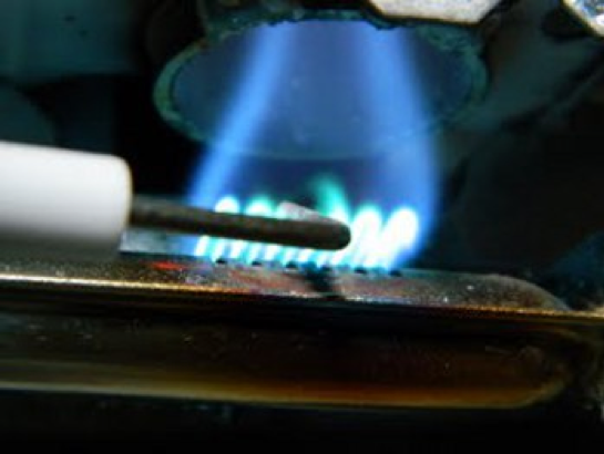 A fridge igniter electrode held against a flame.