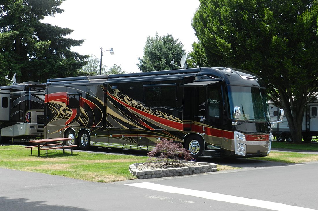 A motorhome with exterior painting parked amid lush landscaping.