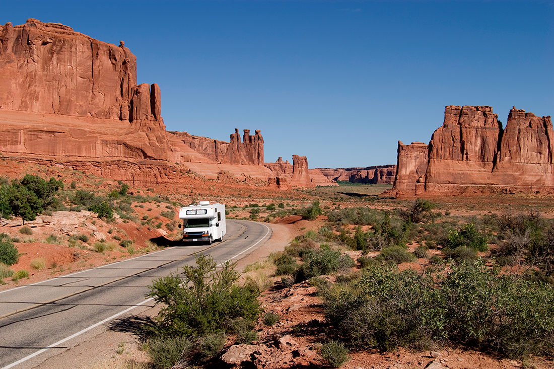 A Class C motorhome driving through Arches National Park in Utah.