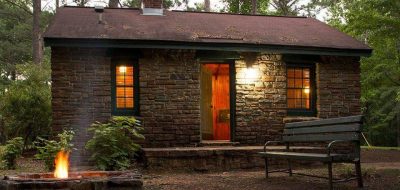 A welcoming cabin emates golden light in the forest dusk.