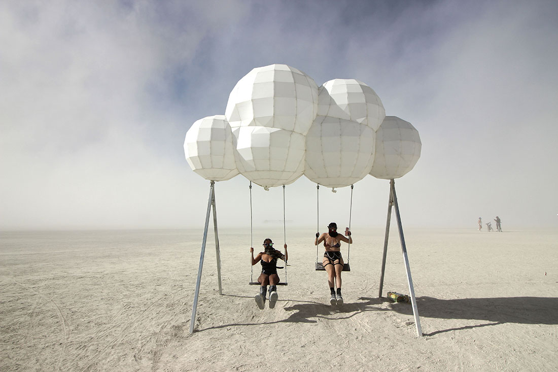 Two women dressed an apocalyptic gear play on futuristic a swing set.