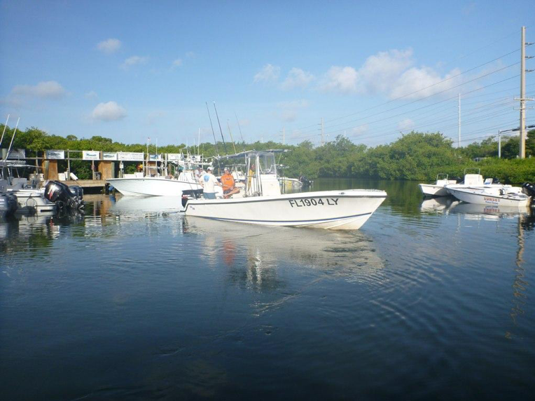 A small fishing charter prepares to embark into the ocean with poles ready for deployment.
