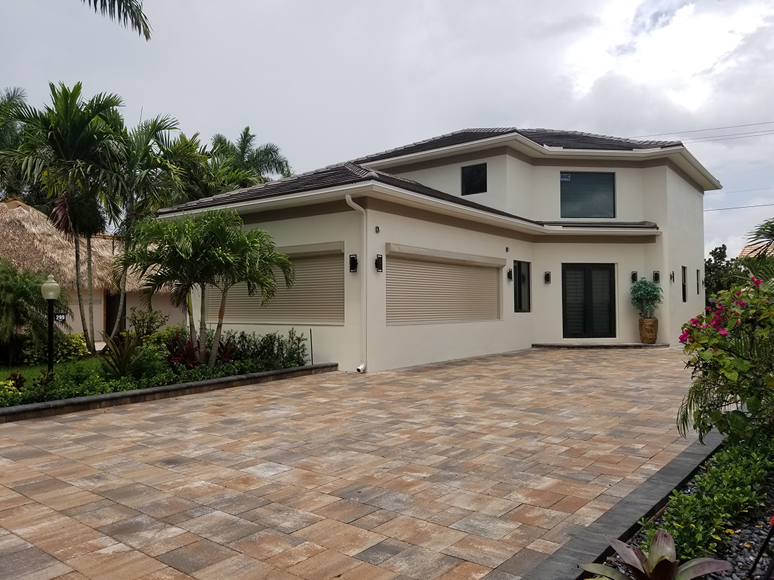 A two-story residential house with a earth-colored brick driveway.