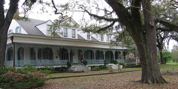 Historic mansion with wrought-iron railings on porch.