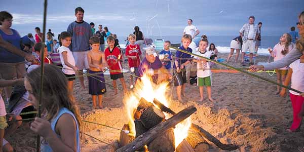 People roasting marshmallows at a beach bonfire