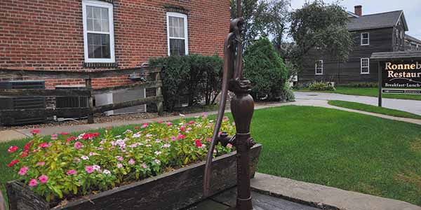 An old water pump next to a planter filled with flowers.