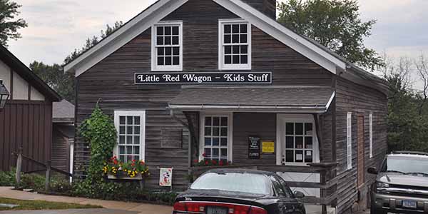 A wooden building with a sign saying, "Little Red Wagon — Kids Stuff"