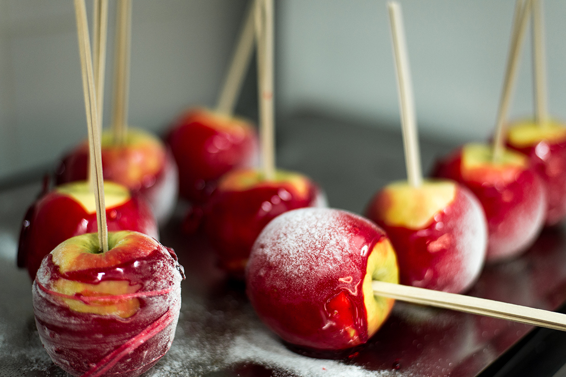 Homemade candy apples with powder sugar on sticks on blur background