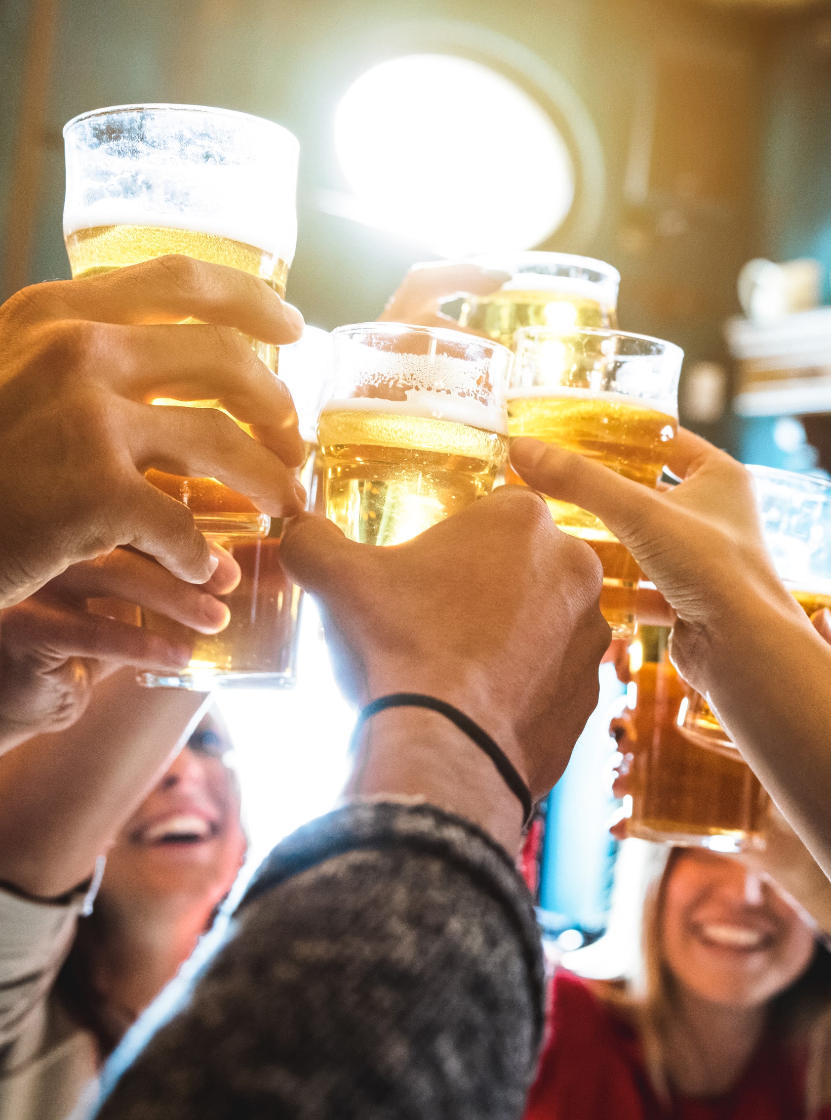 A number of folks holding beer glasses raise their hands for a toast.