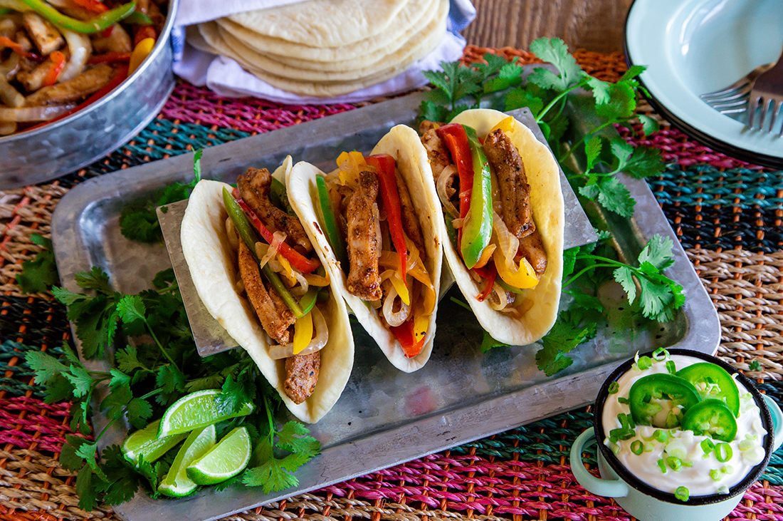 Pressure cook flavorful fajitas — A row of three fajitas filled with meat and cooked peppers.