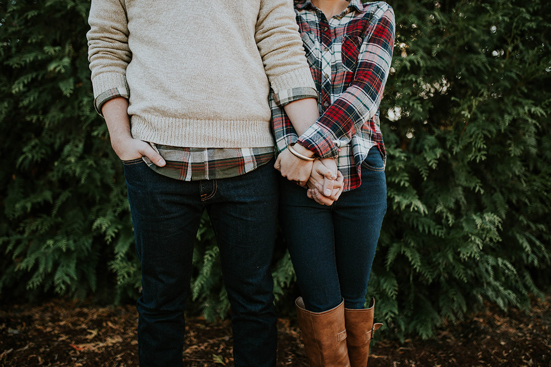 A couple wearing layers hold hands in cool weather.