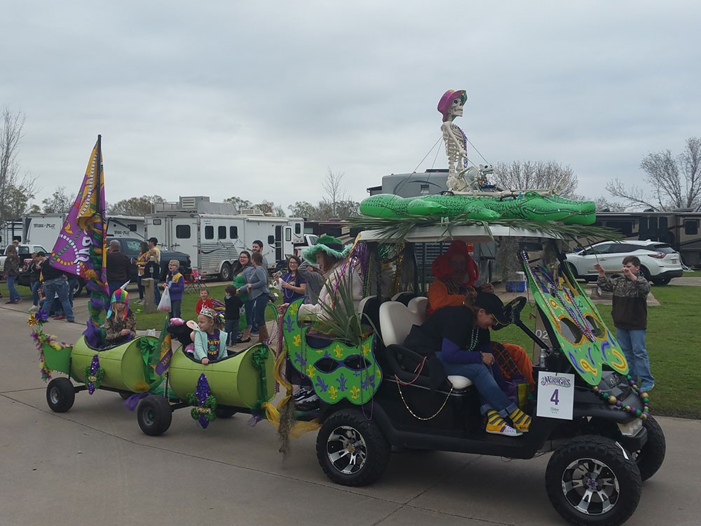 An ATV pulls two cars as part of a kid-friendly Mardi Gras parade.