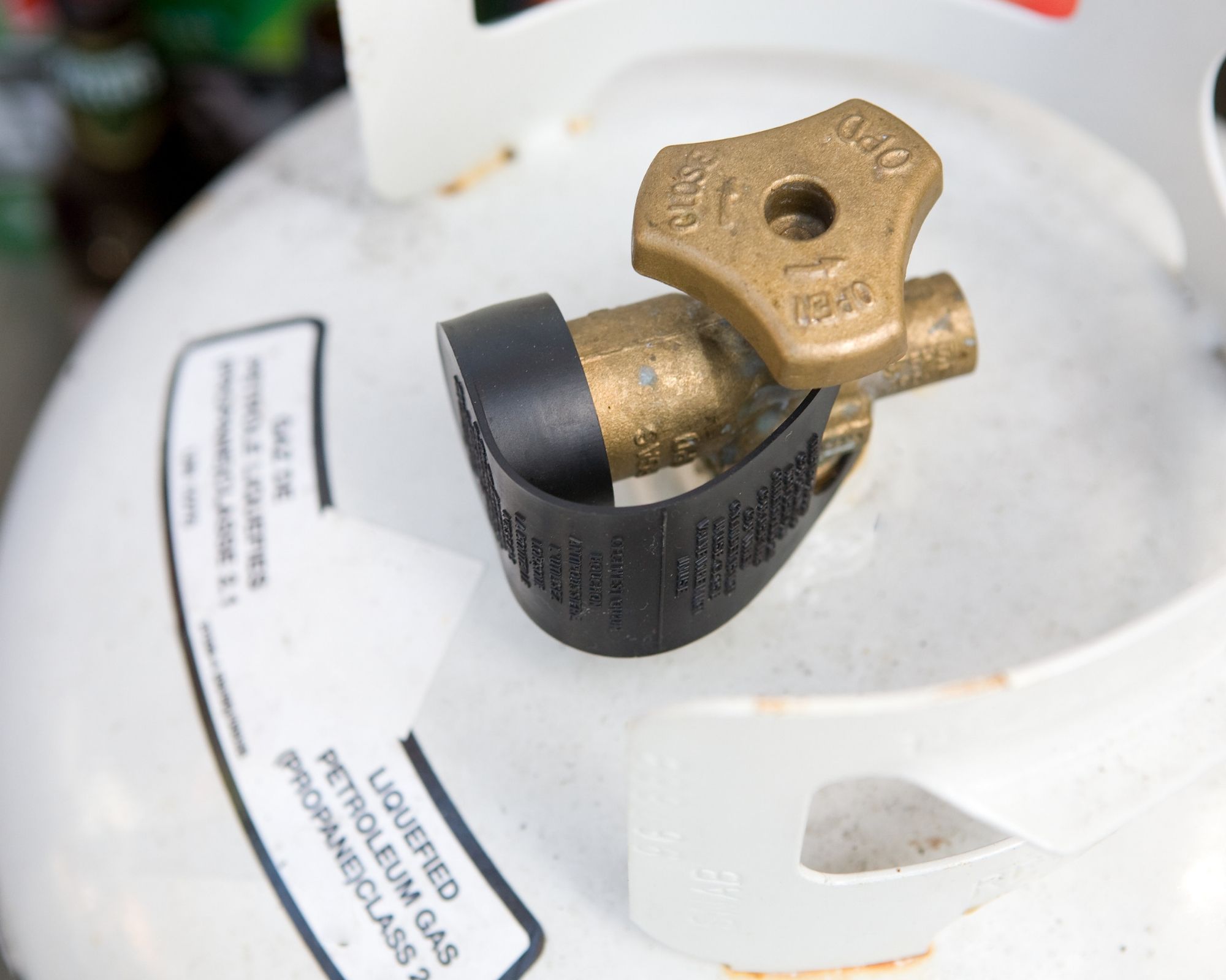 Closeup of a propane valve attached to a white cylinder.