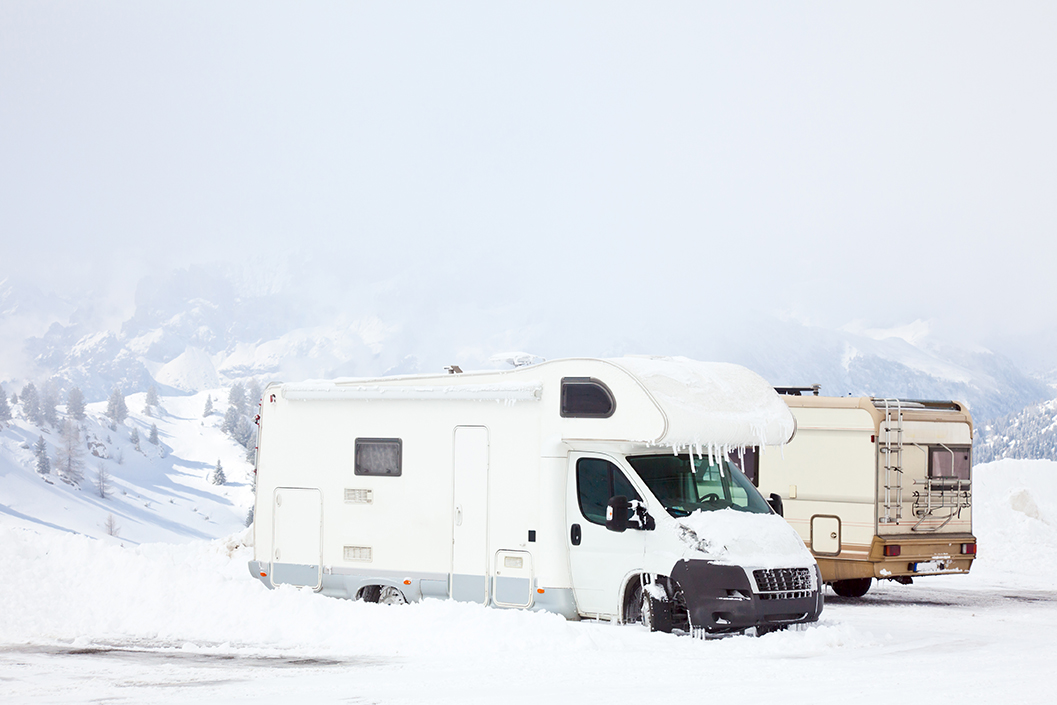 An RV covered with snow with icicles.