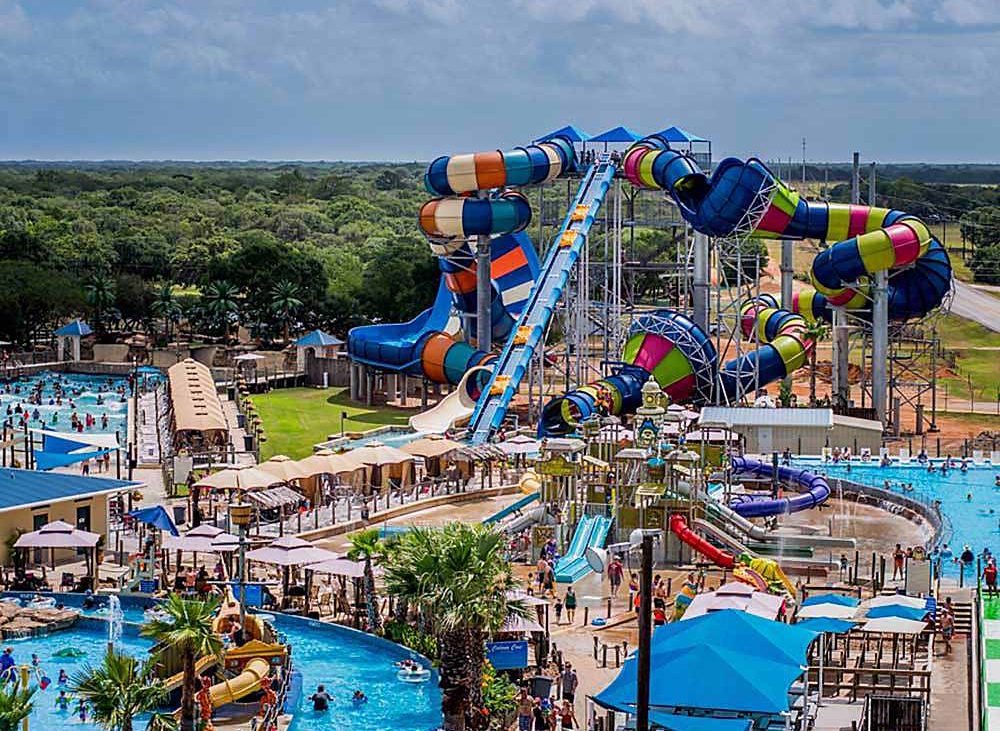 A colorful complex of water slides and pools with bathers cavorting in all the fun.