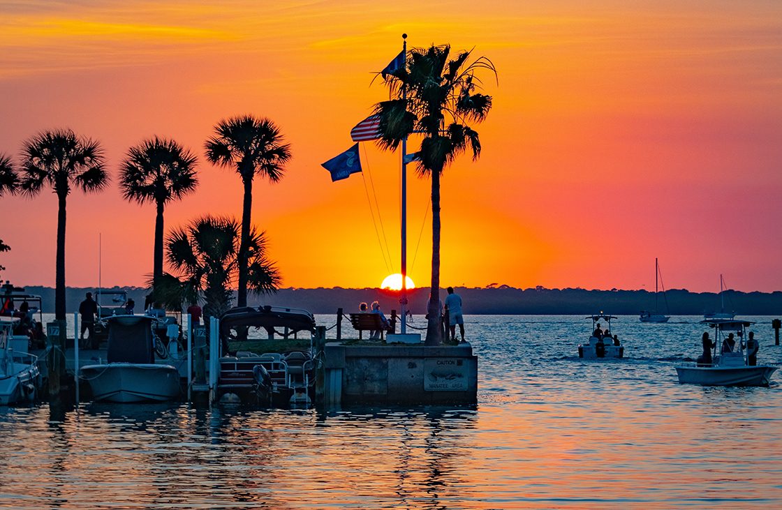 New Good Sam Parks September — Sunset over boats with silhouetts of palm trees.