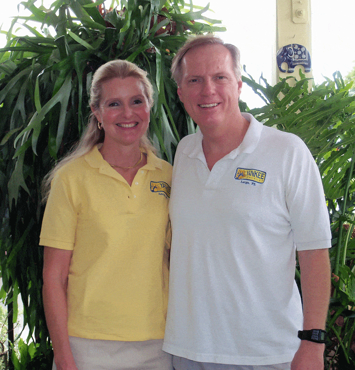 A middle-aged man and woman smile for the camera wearing Yankee Traveler shirts.