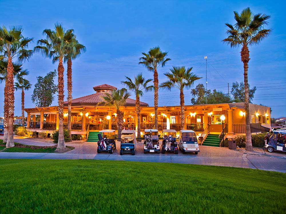 An Arizona resort under tall palms turns on its light as dusk descends.