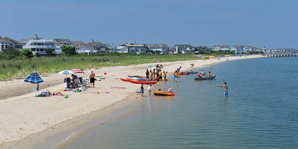 Beachgoers launch rafts on a calm ocean shore.