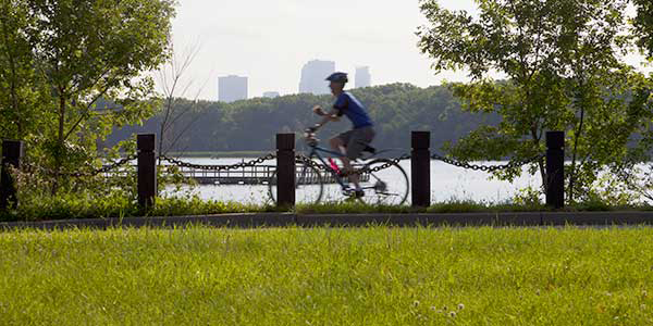 A cyclist rides along the banks of a lake.