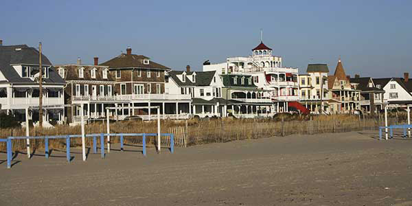 A row of turn-of-the-century-style houses facing the ocean shore.