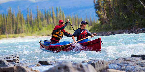 Two paddlers guide a canoe through whitewater.