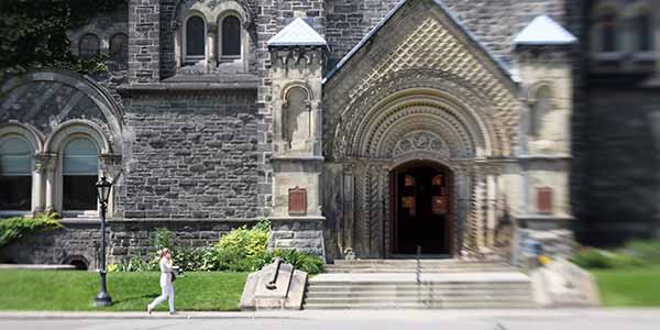 A girl walking in front of the University of Toronto