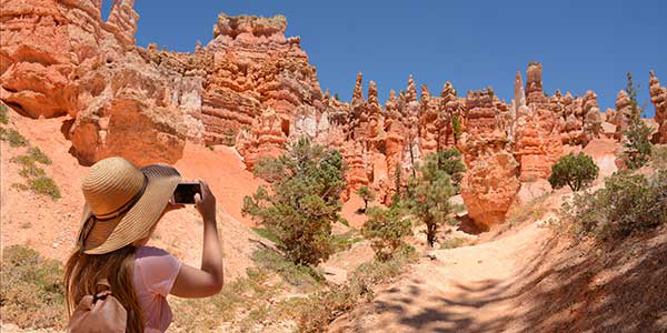 Woman takes photographs of erie rock hoodoos in Bryce.